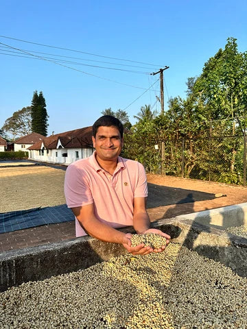 Sunil with freshly cured green coffee on the drying yard